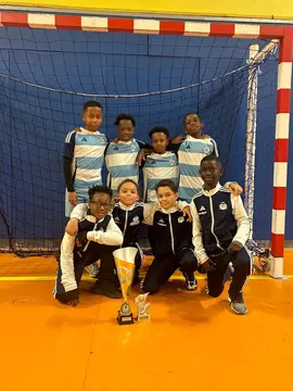 Jeunes du VFA posant avec leur trophée dans un gymnase